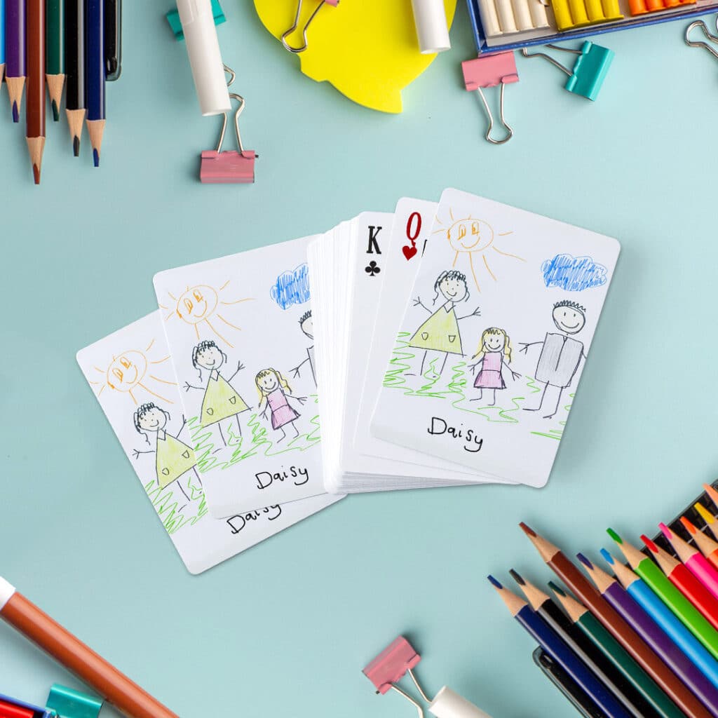 A set of playing cards with a children drawing of a family on the back of cards