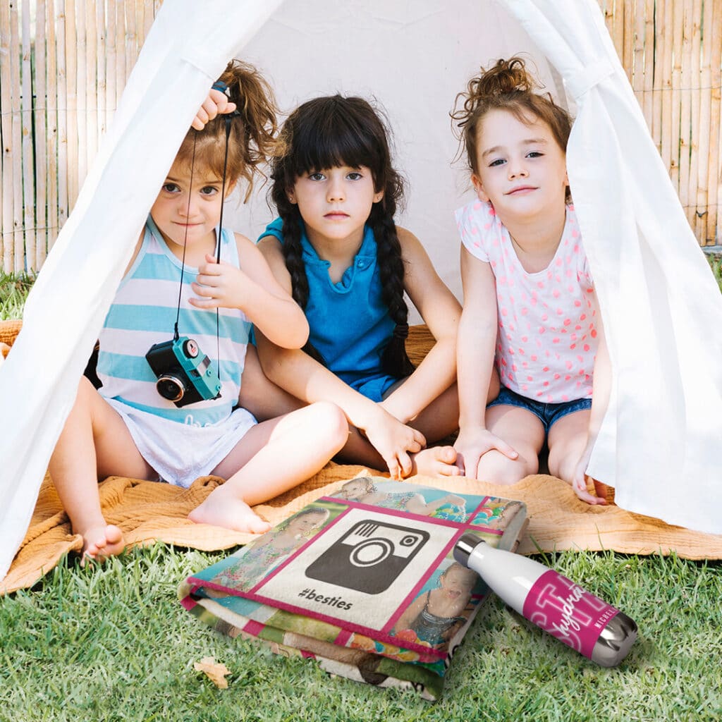 A personalised blanket and a water bottle in front of three little girls camping in a tent