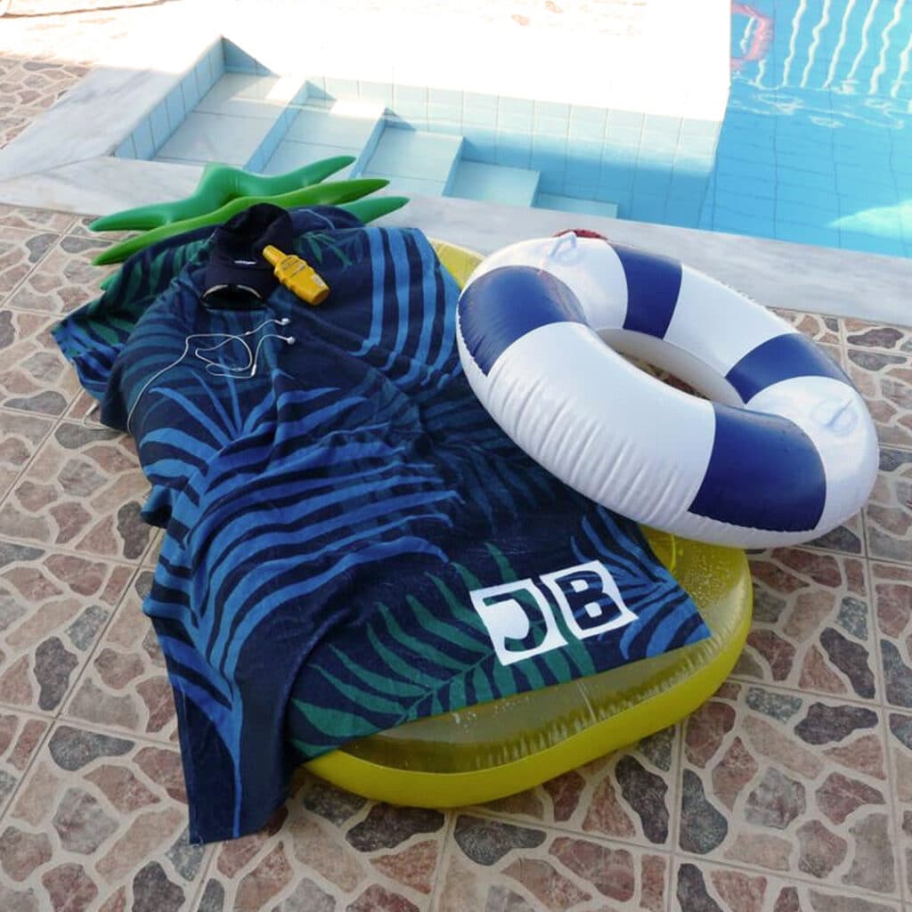 A personalised beach towel in front of a pool
