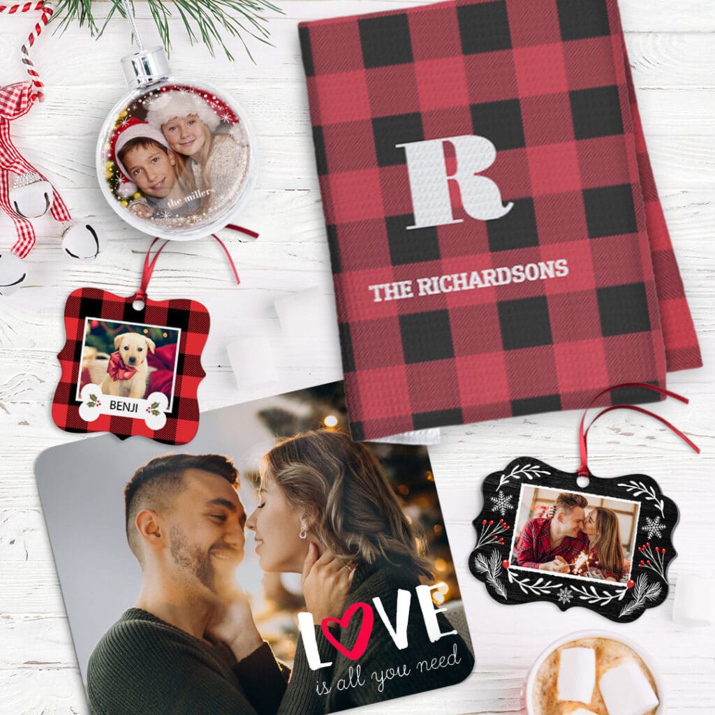 A selection of Christmas ornaments next to a placemat with a couples image and a personalised kitchen towel
