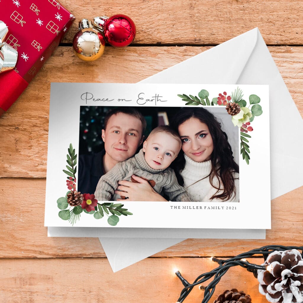 a Merry Christmas greeting card presented on a surface with Christmas gift, baubles and lights
